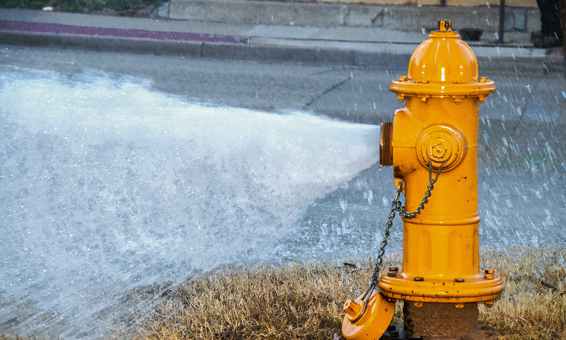Yellow hydrant spraying water on street