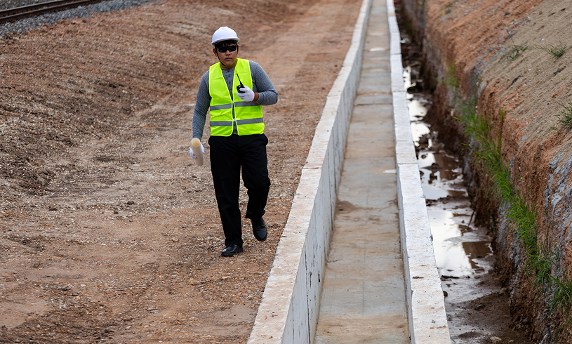Worker with safety vest near trench.