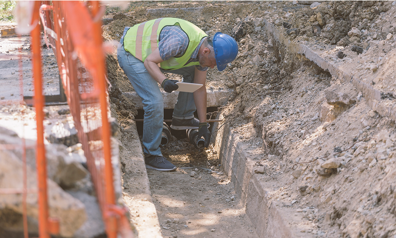 Man digging in construction site trench